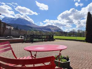 uma mesa rosa e um banco e montanhas ao fundo em North Face Dwelling at Ardenvale Self Catering em Fort William