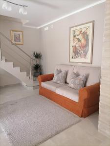 a living room with an orange couch and stairs at SoleLuna in Santa Elisabetta
