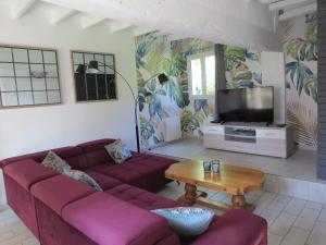 uma sala de estar com sofás vermelhos e uma televisão em Le Gîte du Coin - Maison de vacances avec jardin em Le Bocasse