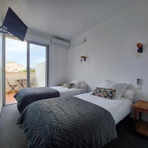 two beds in a room with a balcony at Ezz'Hotel Canet in Canet-en-Roussillon