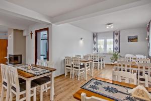 a dining room with tables and white chairs at Willa Harnikówka in Białka Tatrzańska