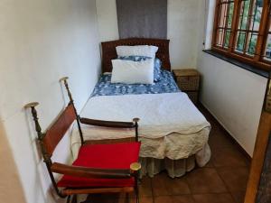 a bedroom with a bed and a red chair at Quaint, quiet retro charm in Johannesburg