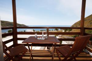 a wooden table and chairs on a balcony with the ocean at Mistral-Patmos in Patmos