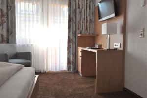 a hotel room with a television and a couch at Hotel-Pension-Jasmin in Rheinfelden