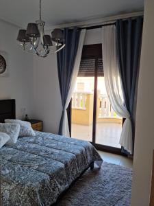 a bedroom with a bed and a large window at AGRADABLE ADOSADO CON PISCINA in Ciudad Quesada