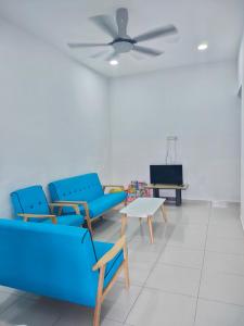 a living room with blue furniture and a ceiling fan at TheREHAT Homestay Kijal Terengganu in Kijal