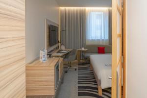 a hotel room with a bed and a desk at Novotel Wien City in Vienna