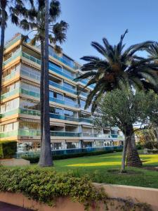 un bâtiment avec des palmiers en face de celui-ci dans l'établissement 4-Star Beachfront Appartment- Sea View, à Cannes