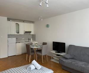 Una sala de estar con un sofá y una mesa y una cocina. en Apartment Green - Grey, en Liubliana
