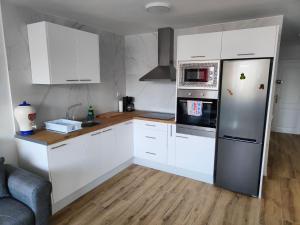 a kitchen with white cabinets and a stainless steel refrigerator at Residencial Los Molinos con piscina, TV internacional y Wifi in Playa del Ingles