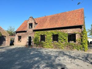 een bakstenen gebouw met klimop aan de zijkant bij Hoeve Hooierzele in Waasmunster