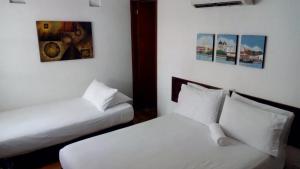 a room with two beds and paintings on the wall at Casa Marqués del Pedregal in Cartagena de Indias