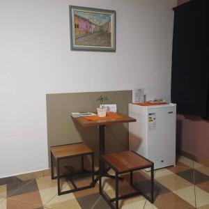 un tavolino e due sgabelli accanto a un frigorifero di Casa Alamanda - Posada Urbana a Ciudad del Este