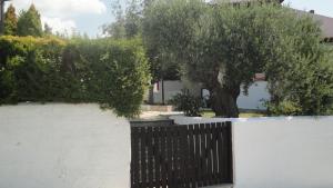 Una pared blanca con una valla negra y un árbol. en Casa De Vacacion, en Gerakini