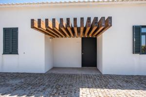a white building with a black door and a brick driveway at Casas São João by Ana Ferro Rentals in Arcozelo