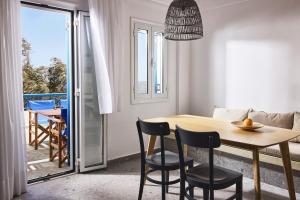 a dining room with a table and chairs and a balcony at Tramontana Suites in Áyios Stéfanos