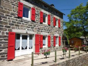 un edificio de ladrillo con ventanas rojas con persianas y flores en Gîte Les Estables, 4 pièces, 6 personnes - FR-1-582-143, en Les Estables