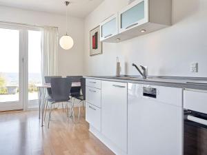 a kitchen with white cabinets and a table with chairs at Holiday home Allinge XXII in Allinge
