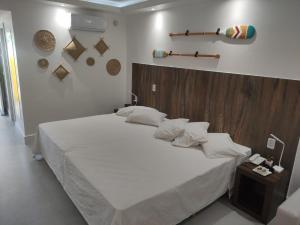 una camera da letto con un grande letto bianco con testiera in legno di Búzios Beach Resort Residencial 1305 a Búzios