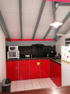 cocina roja con armarios rojos y microondas en Résidence BLEUE DE MER en Deshaies
