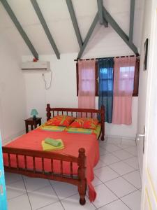 1 dormitorio con 1 cama con sábanas rojas y almohadas de color naranja en Résidence BLEUE DE MER en Deshaies