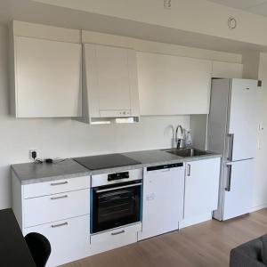 eine Küche mit weißen Schränken und einem Kühlschrank in der Unterkunft Scandpoint Apartment Fornebu Near Sea front with outdoor walk! in Stabekk