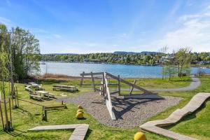 a park with a playground next to a lake at Scandpoint Apartment Fornebu Near Sea front with outdoor walk! in Stabekk