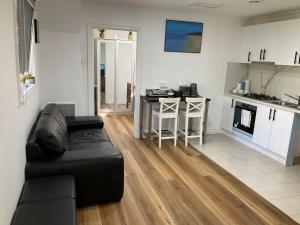 a living room with a black couch and a kitchen at Oakleigh Private unit in Oakleigh