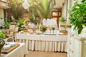 a restaurant with white tables with food and plants at Golden Royal Boutique Hotel & Spa in Košice