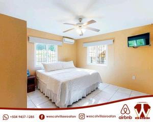 a bedroom with a bed and a ceiling fan at Wescot Villas Comfort in Roatán