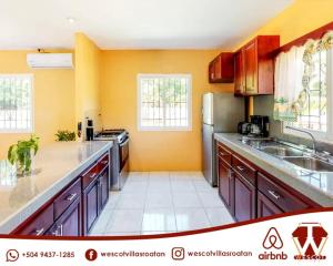 uma cozinha com paredes cor de laranja e electrodomésticos em aço inoxidável em Wescot Villas Comfort em Roatán