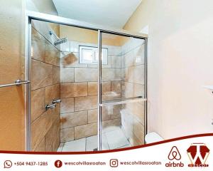a shower with a glass door in a bathroom at Wescot Villas Comfort in Roatán