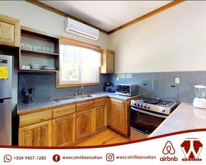 a kitchen with wooden cabinets and a sink and a stove at Wescot Villas Sky View in Roatán