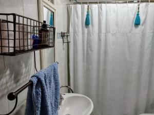baño con cortina de ducha blanca y lavamanos en M&A Alquileres en Mercedes
