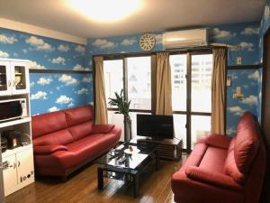 a living room with two red couches and a tv at Cozy Family room KY apartment in Naha