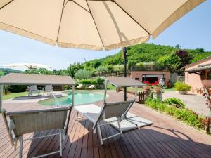 una terraza con sombrilla y sillas y una piscina en Belvilla by OYO Villa Angolo Fiorito en Urbino