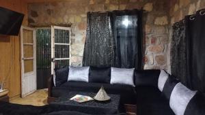 a living room with a black couch and a window at Ferme Tibrijine in Marrakech