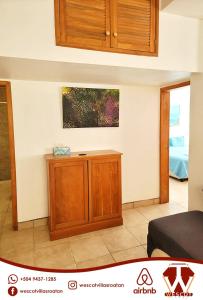 a living room with a wooden cabinet in a room at Sunset Waves in Roatan