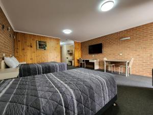 a hotel room with two beds and a table and a tv at Country Roads Motor Inn Naracoorte in Naracoorte