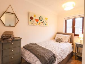 a bedroom with a bed and a dresser and a mirror at 1 Barbers Row in Elmswell