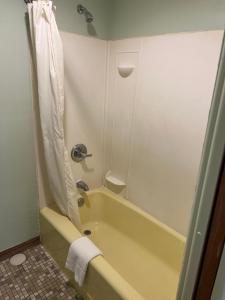 a bathroom with a yellow tub and a shower at Town & Country Motel in Clinton