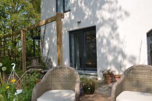 2 chaises en osier assises sur une terrasse en bois dans l'établissement La cave au chat'pitre / l'étable, à Villers-le-Bouillet