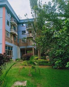 an apartment building with a garden in front of it at NdamaRosa River Park Resort in Migori