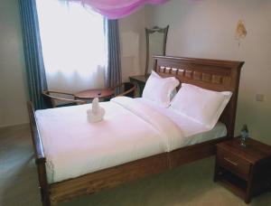 a bedroom with a bed with white sheets and a window at NdamaRosa River Park Resort in Migori
