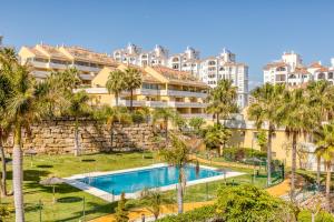widok na budynek z basenem i palmami w obiekcie Hanami Puerto Alto PA 4-4 w mieście Estepona