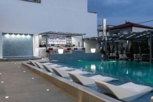 a swimming pool with white chairs and a bar at Aeonian Luxury Suites Asprovalta, Adults Only & Kids 12 Plus in Asprovalta