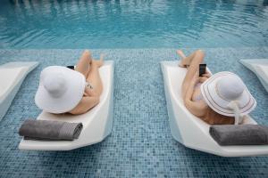 a woman laying in a chair next to a swimming pool at Aeonian Luxury Suites Asprovalta, Adults Only & Kids 12 Plus in Asprovalta