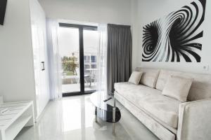 a white living room with a couch and a glass table at Aeonian Luxury Suites Asprovalta, Adults Only & Kids 12 Plus in Asprovalta
