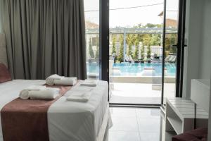 a hotel room with a bed and a view of a pool at Aeonian Luxury Suites Asprovalta, Adults Only & Kids 12 Plus in Asprovalta