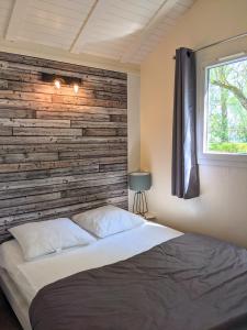 1 dormitorio con una pared de madera y 1 cama en Camping Du Port De Plaisance, en Péronne